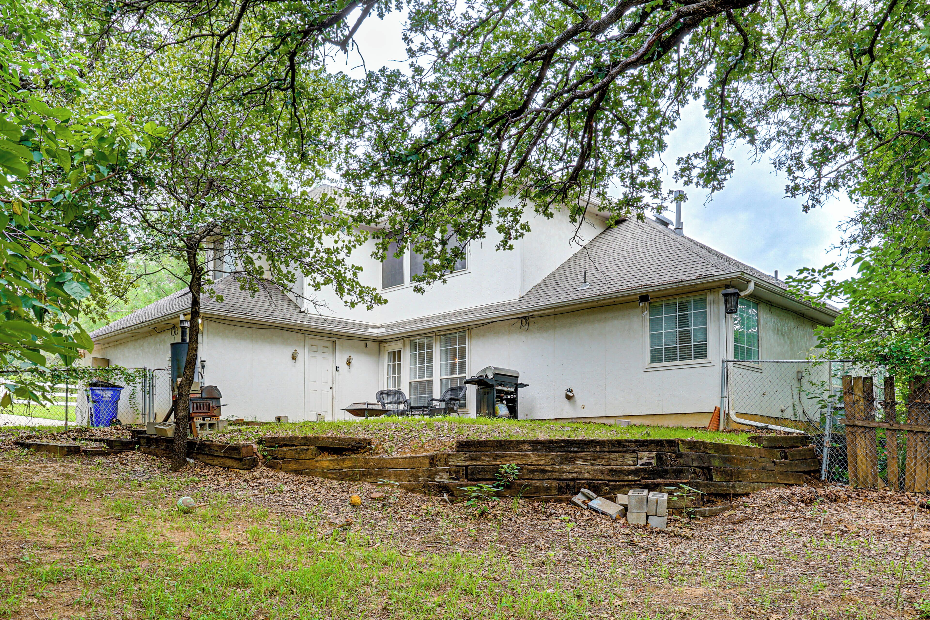 A single-story house with a front yard, a barbecue grill, and a trash can.