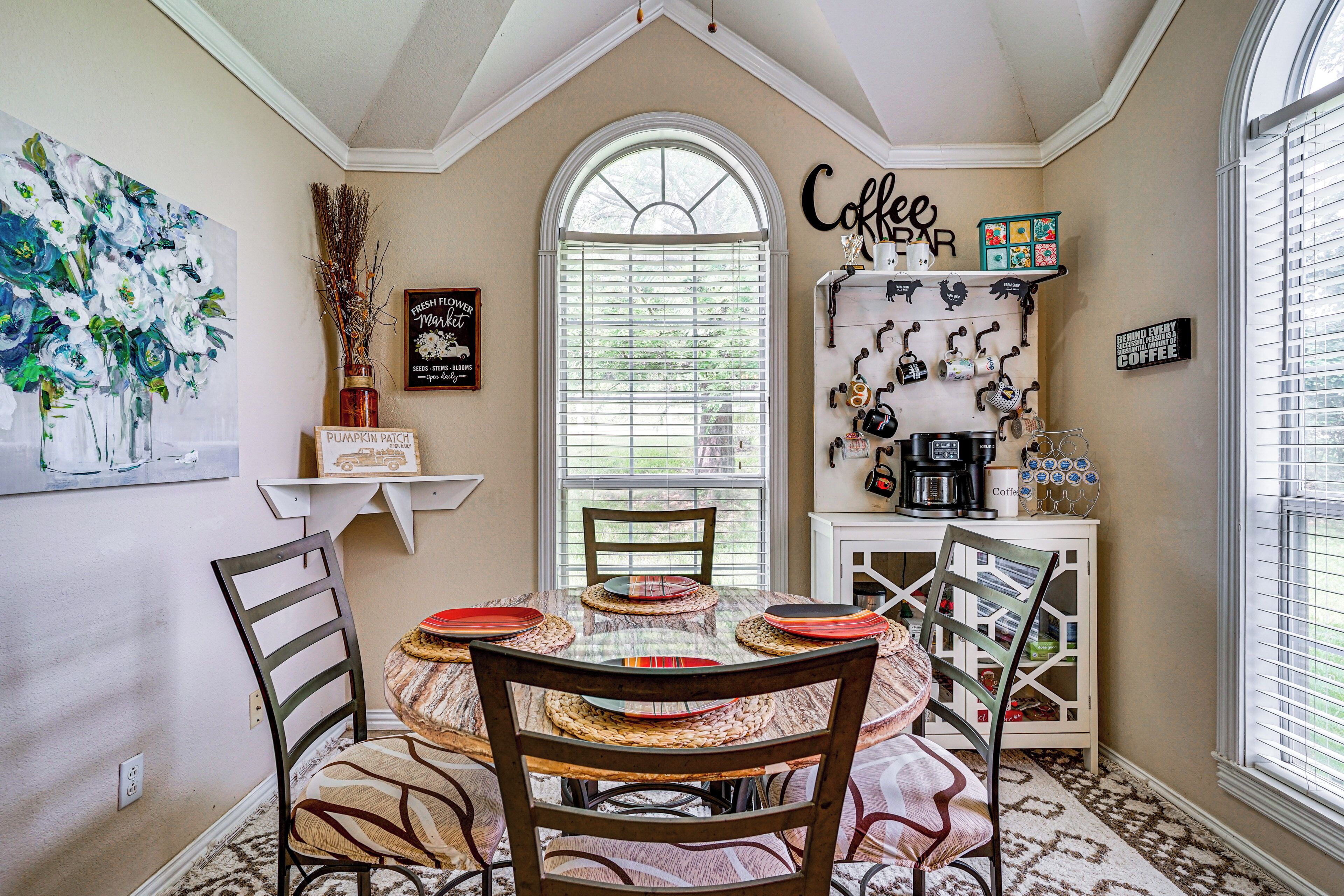 A dining area with a round table, chairs, and a coffee station.