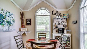 Een eethoek met een ronde tafel, stoelen en een koffiehoek.