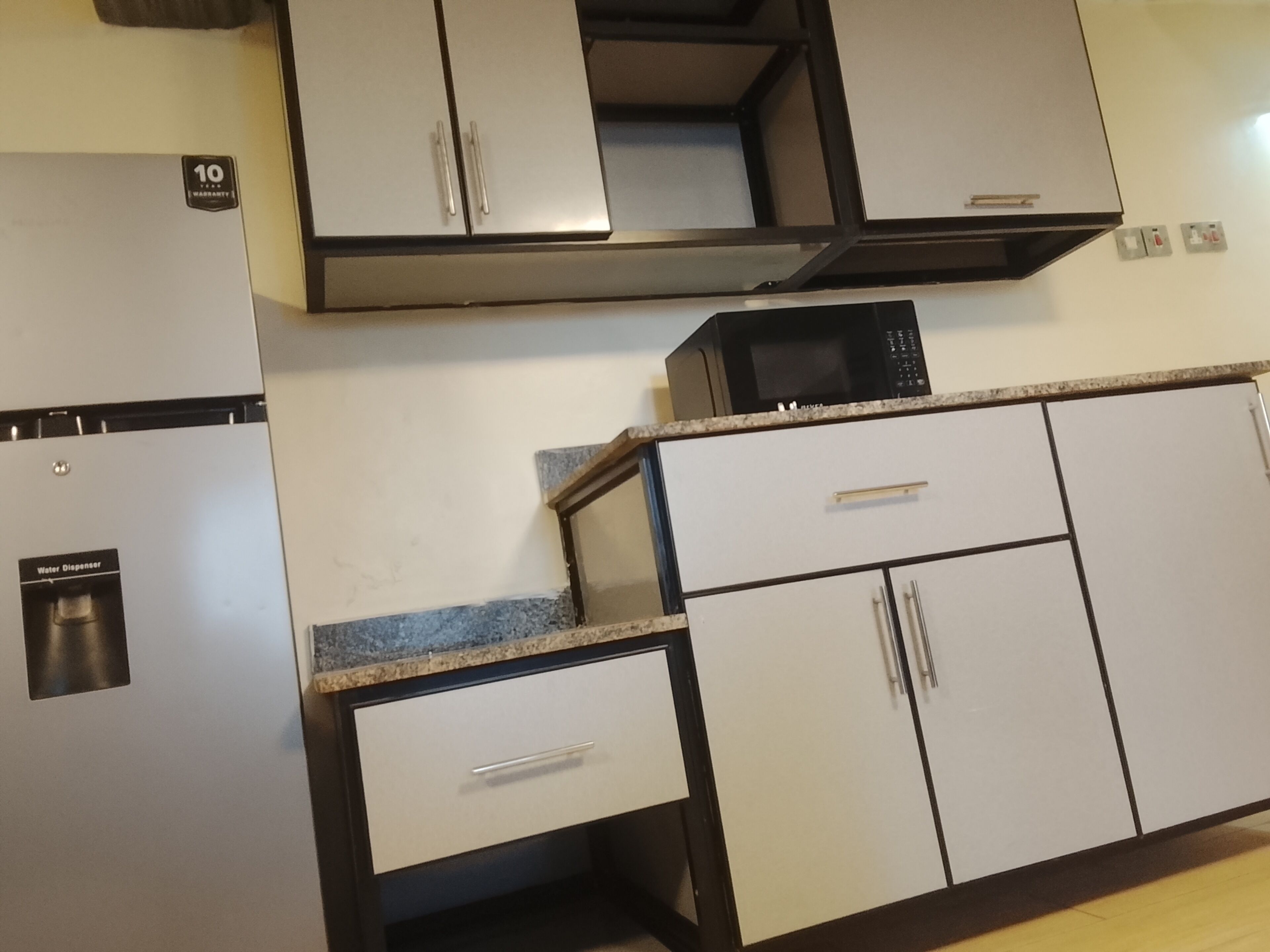 A kitchen with a refrigerator, microwave, and cabinets.