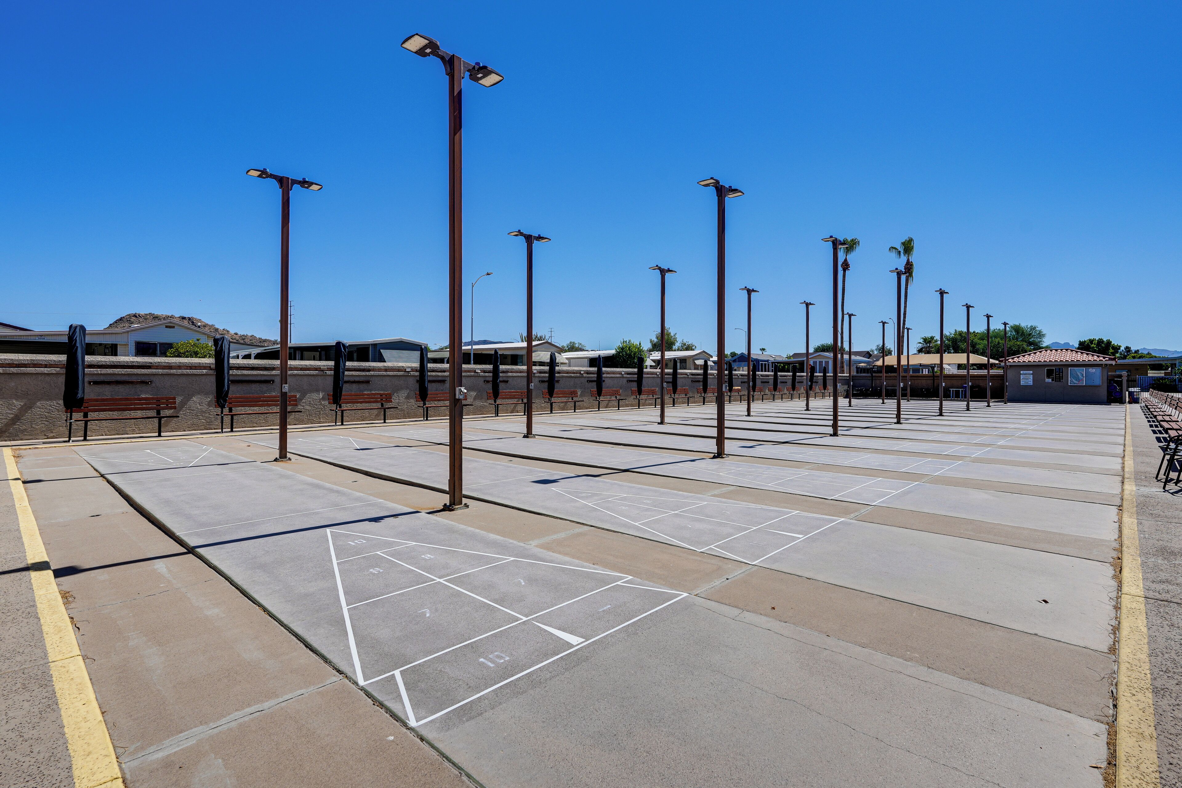 A parking lot with marked parking spaces, benches, and street lamps.