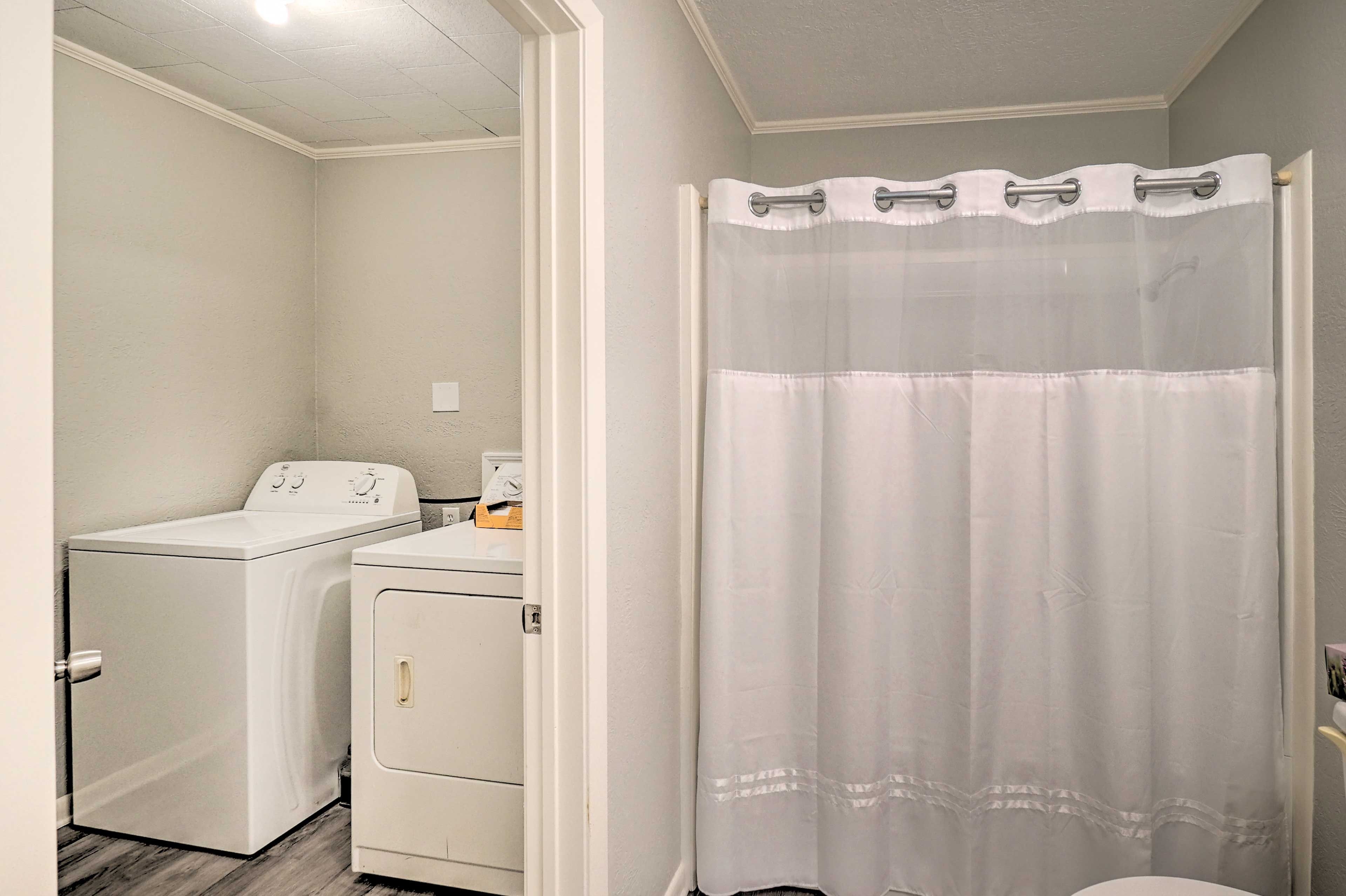 Une buanderie équipée d’un lave-linge et d’un sèche-linge, d’un rideau de douche et de toilettes.