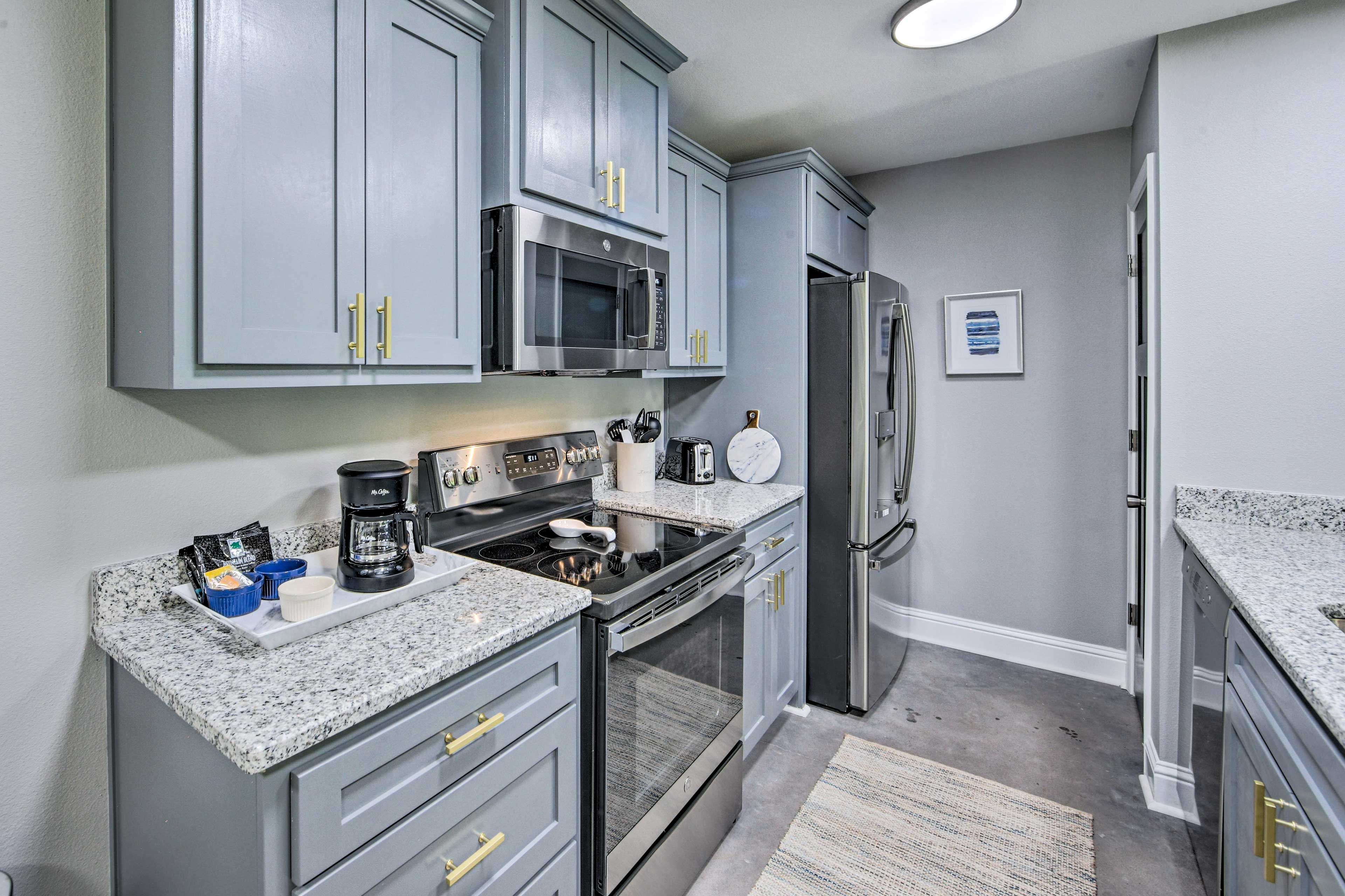 A modern kitchen with grey cabinets, stainless steel appliances, and granite countertops.