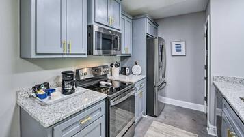 A modern kitchen with grey cabinets, stainless steel appliances, and granite countertops.
