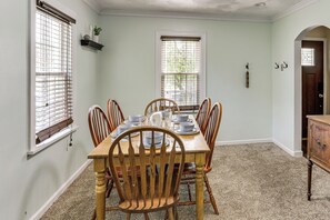 A dining room with a wooden table set for six, flanked by two windows with blinds, a dark wooden cabinet, and a door with a glass panel. - Timeless Charm in the Heart of Steubenville (Steubenville)