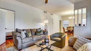 A living room with a sofa, armchair, coffee table, and a dining area with a table and chairs. - Fenced Yard! Quiet Home, 3 Mi to Dtwn El Paso (El Paso)