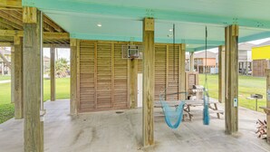 A covered outdoor area with wooden beams, a basketball hoop, a hammock, and a picnic table. - Bolivar Peninsula Beach House: Family Friendly! (Port Bolivar)