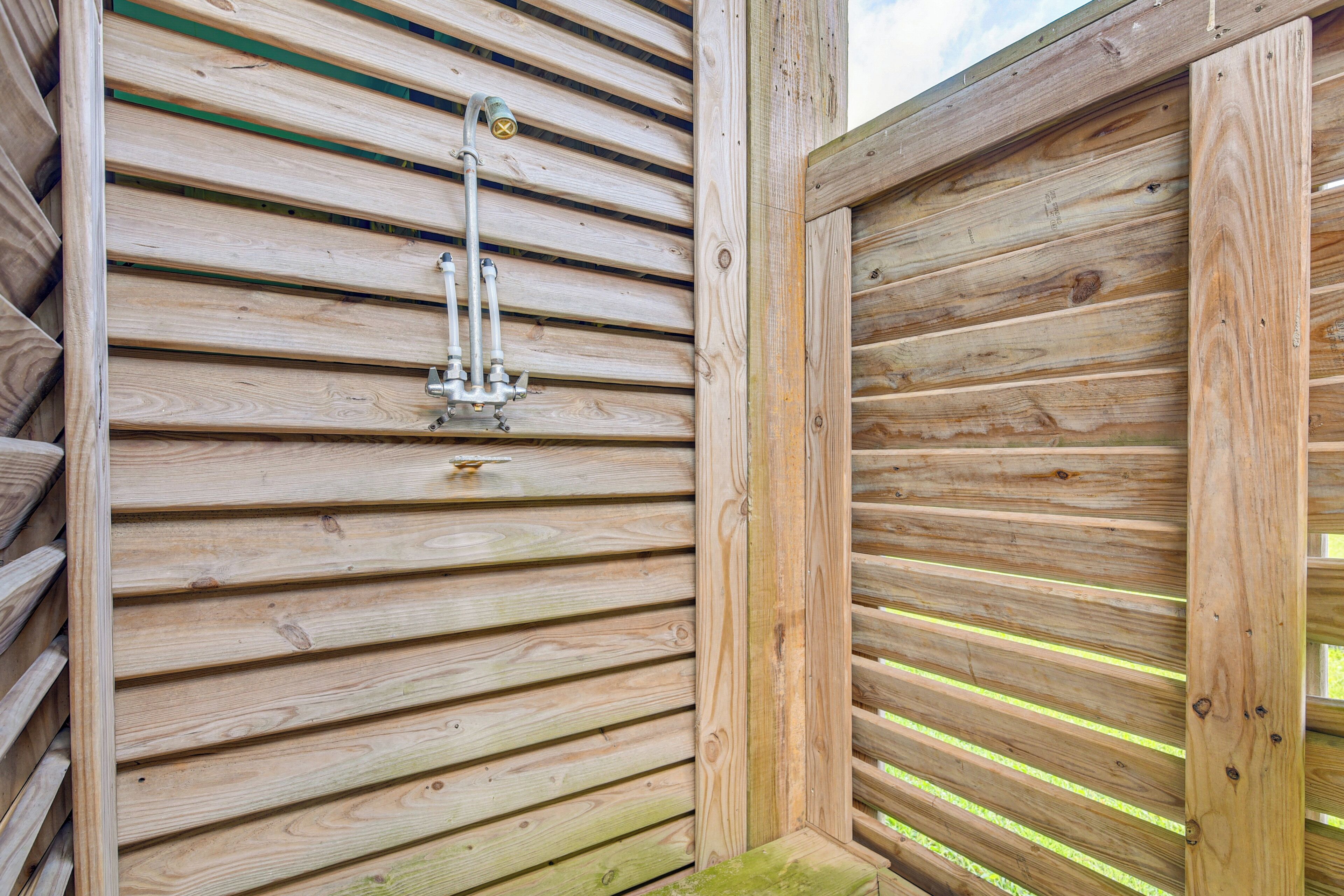 A wooden cabin with horizontal slats, a metal faucet, and a wooden door frame.