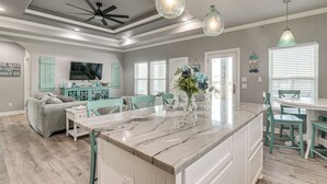 A spacious kitchen with a marble island, teal chairs, and pendant lighting. - Bolivar Peninsula Beach House: Family Friendly! (Port Bolivar)