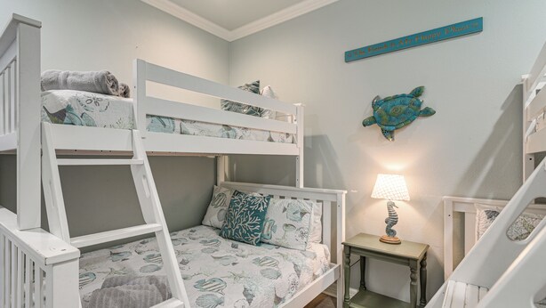A bunk bed room with a small table and a decorative turtle wall art. - Bolivar Peninsula Beach House: Family Friendly! (Port Bolivar)