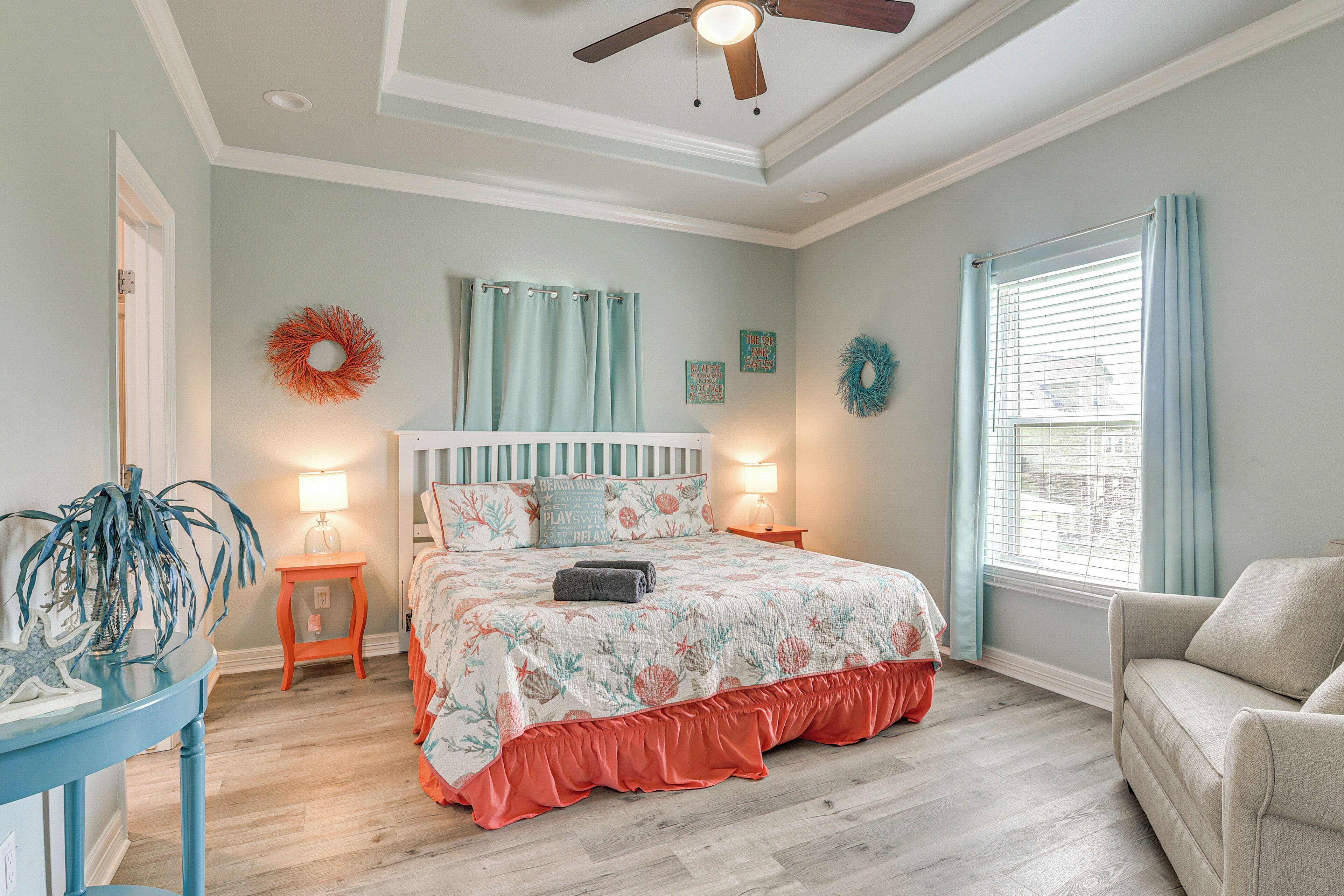 A bedroom with a bed, a nightstand, a chair, a ceiling fan, and a window with curtains.