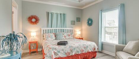 A bedroom with a bed, a nightstand, a chair, a ceiling fan, and a window with curtains.