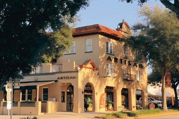 A two-story building with a sign reading 'ARTISAN' and a bell tower.