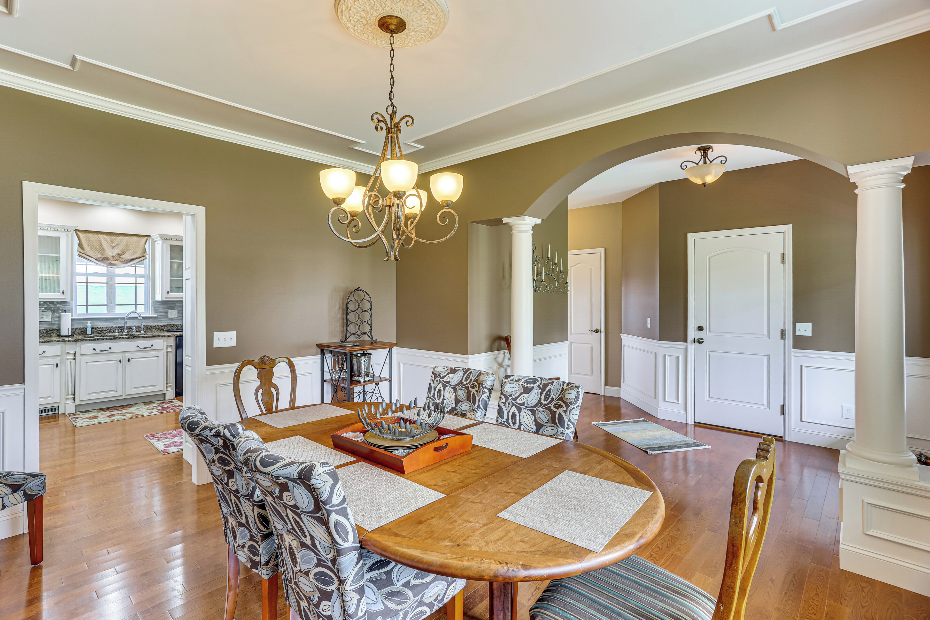 A dining room with a wooden table, patterned chairs, and a chandelier.