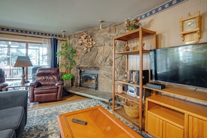 Una sala de estar con chimenea, sillón de cuero, televisor y estanterías de madera.