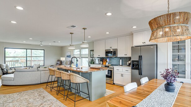 A modern kitchen with a central island, bar stools, and a dining table with a vase of flowers. - Waterfront 2-unit Combo w/ Dock in Dickinson (Dickinson)