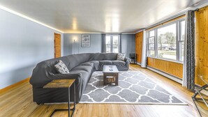 Ein modernes Wohnzimmer mit einem Ecksofa, einem kleinen Couchtisch und einem gemusterten Teppich.