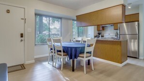 Eine moderne Küche mit Holzschränken, einem Edelstahlkühlschrank und einem Essbereich mit blauer Tischdecke.