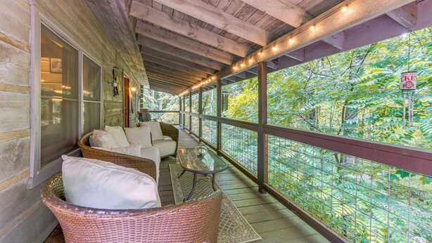 A covered porch with wicker furniture, a glass table, and a view of a forest. - 7 Acres w/ Trails! Waynesville Adventure Hub (Waynesville)
