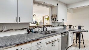 Eine Küche mit weißen Schränken, einer Granit-Arbeitsplatte, einer Spüle und einem Geschirrspüler.