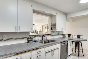 A kitchen with white cabinets, a granite countertop, a double sink, and a dishwasher.