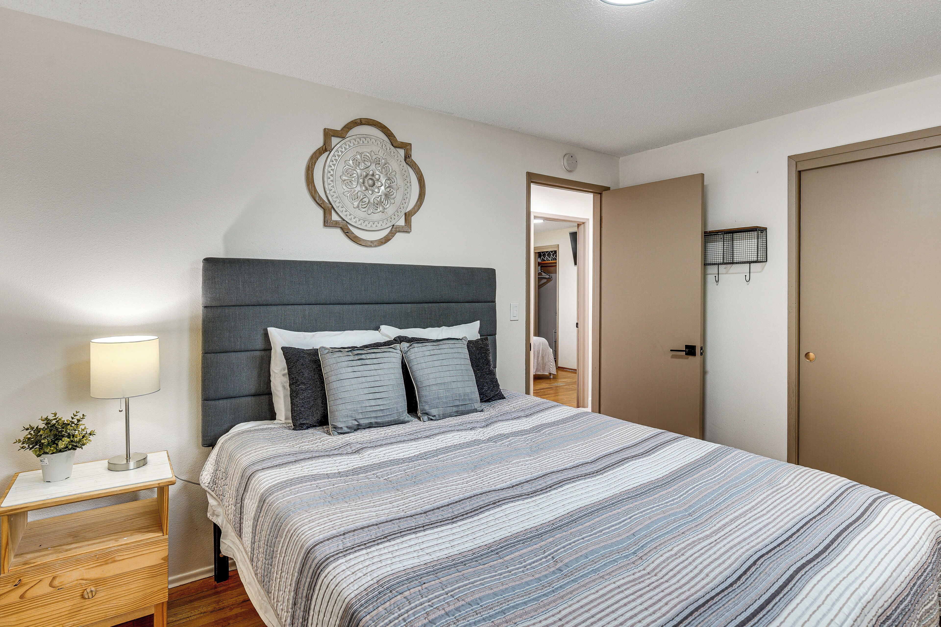 Un dormitorio con cama, mesita de noche, lámpara y un adorno en la pared.