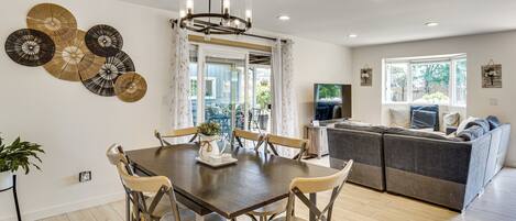 A modern living space with a dining area, sofa, and a large window.