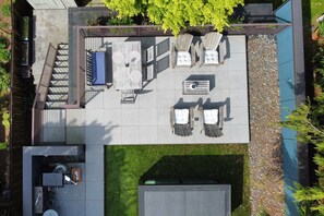 An outdoor patio with a pool table, lounge chairs, and a barbecue area.