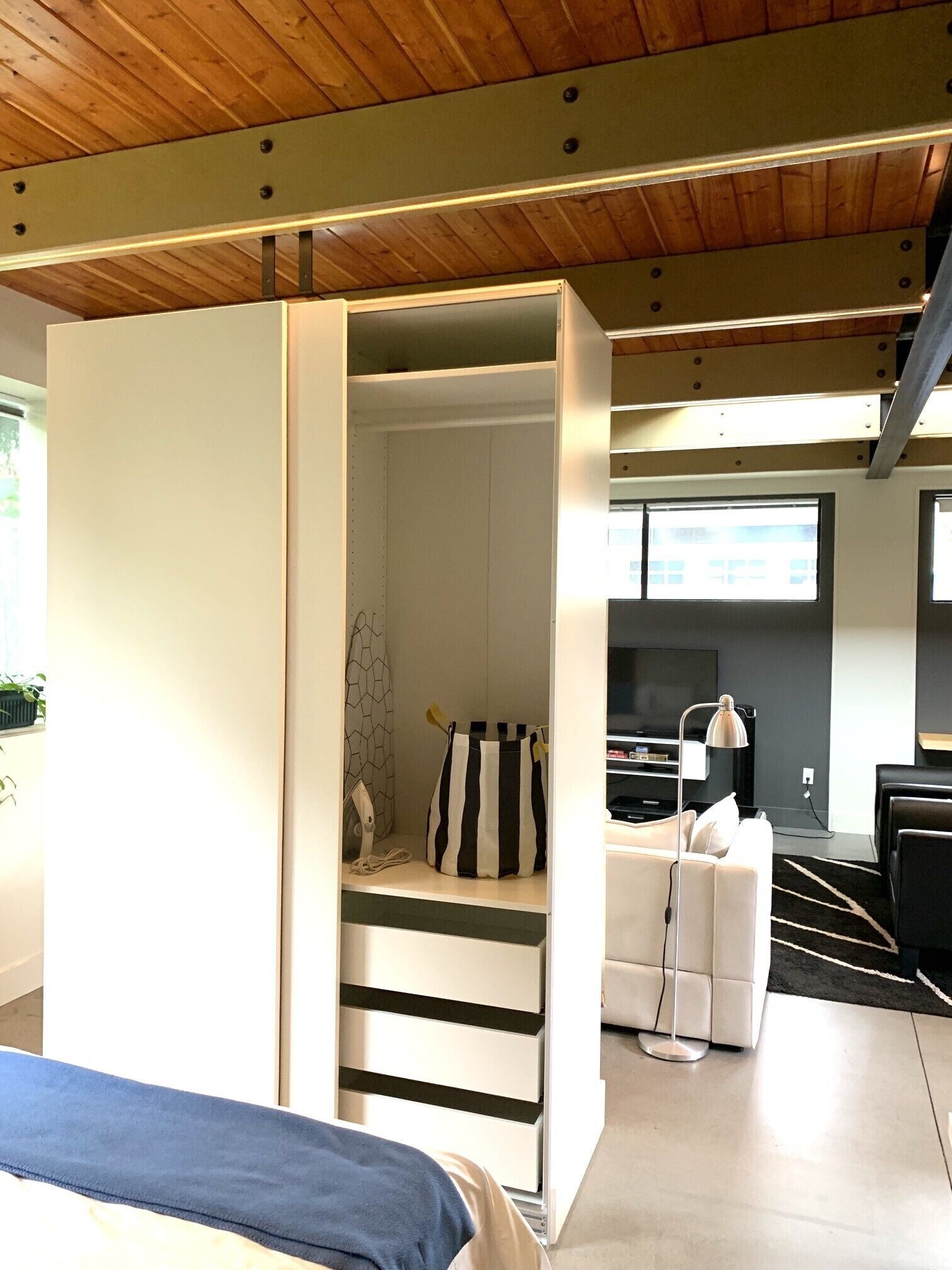 A modern room with a bed, a desk, a TV, and a seating area.