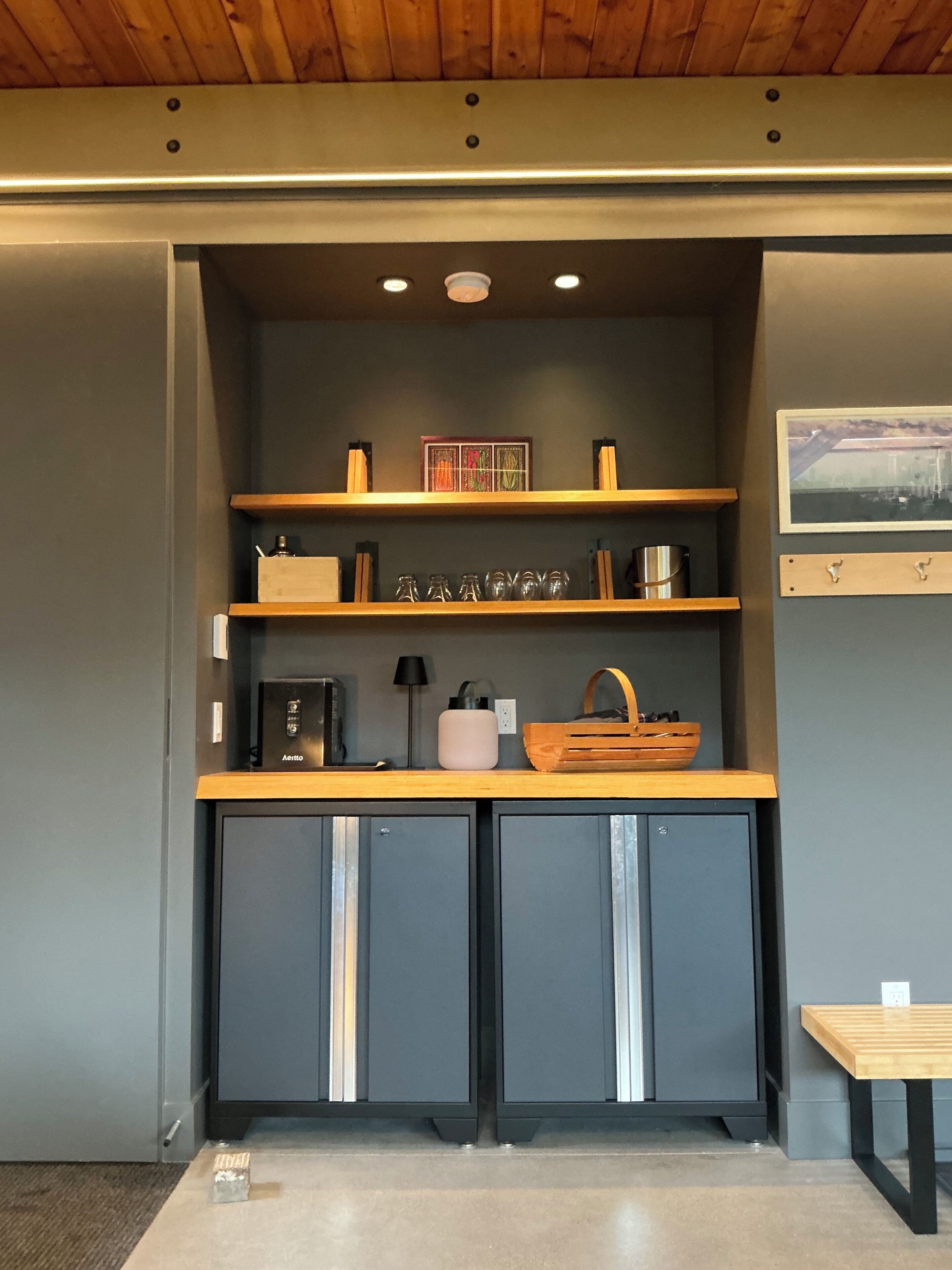 A kitchenette with a coffee machine, a kettle, and a small cabinet.