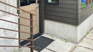 A modern house with a wooden door, a small porch, and a metal staircase.