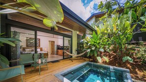 A modern house with a wooden deck, a swimming pool, and lush greenery. - KARÉ: Arenal Exclusive Rainforest - Villa Senda (La Fortuna)
