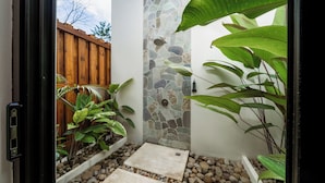 A stone wall, a wooden fence, and potted plants in a courtyard. - KARÉ: Arenal Exclusive Rainforest - Villa Senda (La Fortuna)