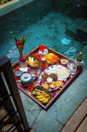 A tray of food and drinks by a poolside.