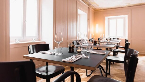 A dining area with tables set for service, large windows, and a classic interior design. - Post Hotel Löwe (Surses)