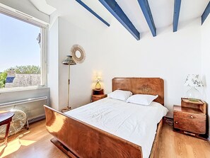 A bedroom with a wooden bed, a floor lamp, a bedside table, and a view of the sky. - Keryargon by Interhome (Belz)