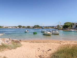 Ein Strand mit Booten, einer Brücke und Häusern im Hintergrund.