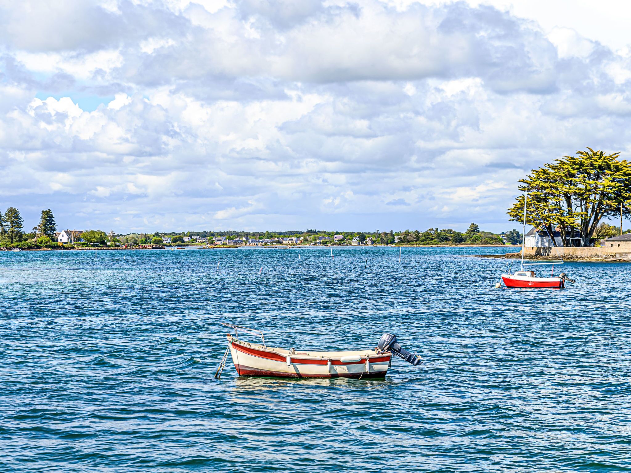 A calm lake with two boats, one anchored and one floating.