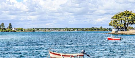 A calm lake with two boats, one anchored and one floating.