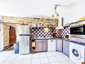 A compact kitchen with a stone wall, a checkered backsplash, a Bosch oven, a dishwasher, and a washing machine. - Keryargon by Interhome (Belz)