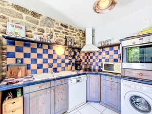 Eine kleine Küche mit Steinwand, karierter Spritzschutzleiste, einem Backofen von Bosch und einer Waschmaschine.