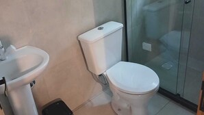Une salle de bain équipée de toilettes, d’un lavabo et d’une poubelle.