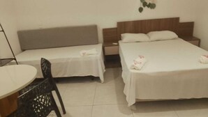 Ein Hotelzimmer mit zwei Betten, einem kleinen Tisch und einem Stuhl.