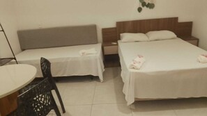 Quarto de hotel com duas camas, uma mesinha e uma cadeira.