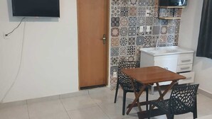 Ein Hotelzimmer mit einem Bett, einem Schreibtisch mit Stuhl, einem Fernseher und einer gefliesten Wand.