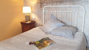 A bed with a metal headboard, a bedside lamp, and a magazine on the bed. - Appartement de charme vue sur mer (Valle-di-Campoloro)