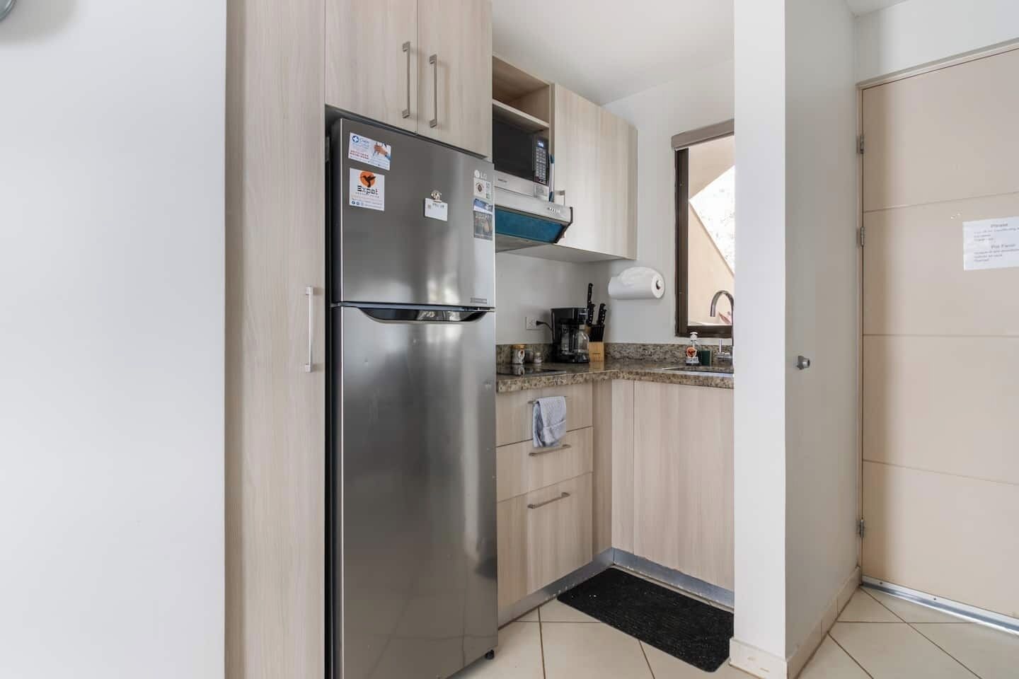 Eine kleine Küche mit einem Edelstahl-Kühlschrank, einer Mikrowelle und einem Spülbecken.