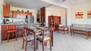 Une cuisine moderne avec des meubles en bois, un coin repas avec une table et des chaises, un canapé et un ventilateur de plafond.