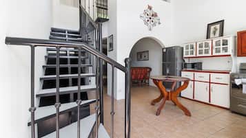 A staircase with metal railings leading to a dining area with a round table and chairs.