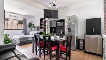 A compact living space with a kitchenette, a dining area, and a bed.